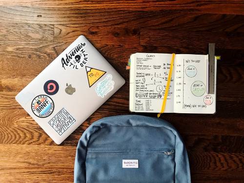 a back pack laptop with stickers and a book