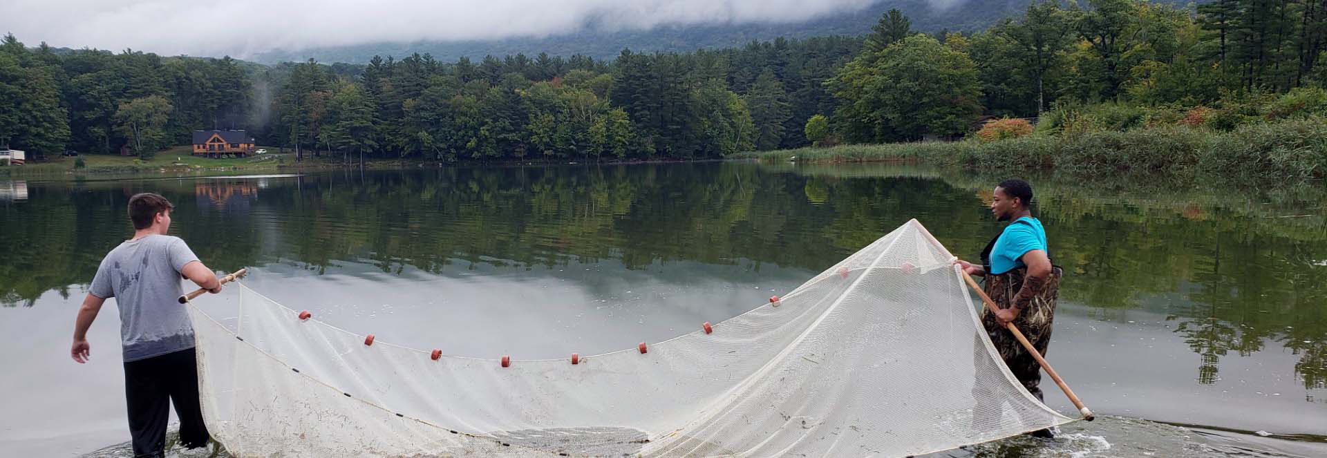 Two environmental study students netting a lake.