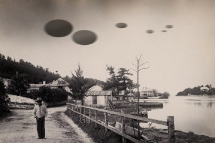 old photograph of a man standing by water with spheres over his head