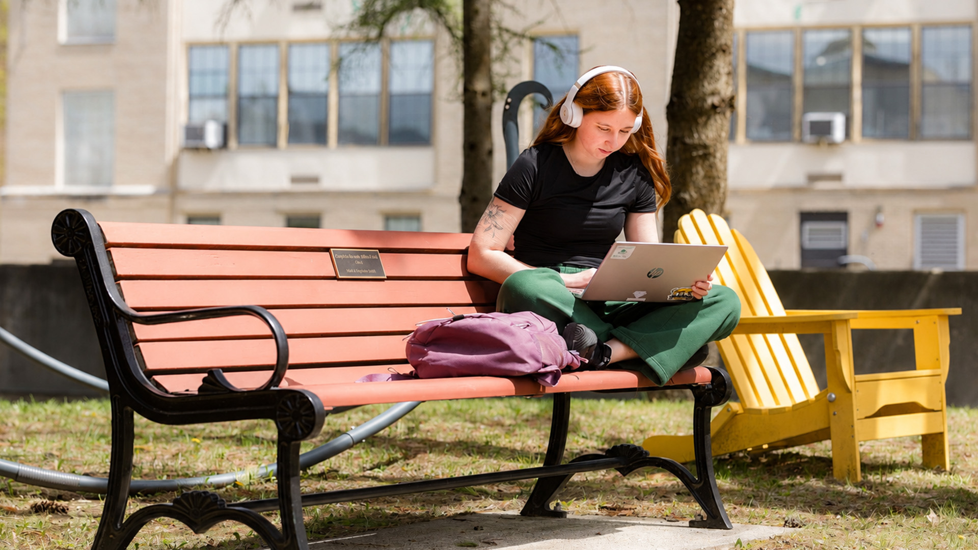 MCLA campus student sitting on a bench outside.